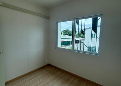 Empty bedroom with a window and wooden floor