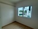 Empty bedroom with a window and wooden floor