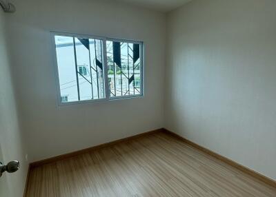 Minimalist bedroom with wooden flooring and a large window