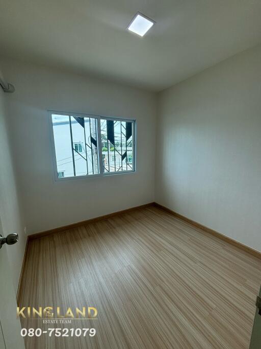 Minimalist bedroom with wooden flooring and a large window