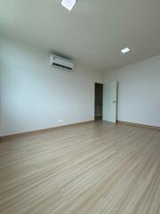 Spacious empty bedroom with wooden flooring and air conditioning