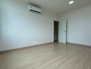 Spacious empty bedroom with wooden flooring and air conditioning