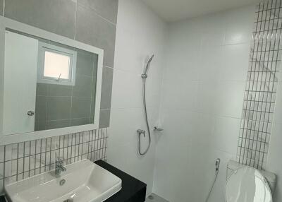 Modern bathroom with a sink, mirror, showerhead, and toilet