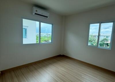 Spacious bedroom with wooden flooring and large windows