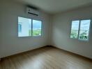 Spacious bedroom with wooden flooring and large windows