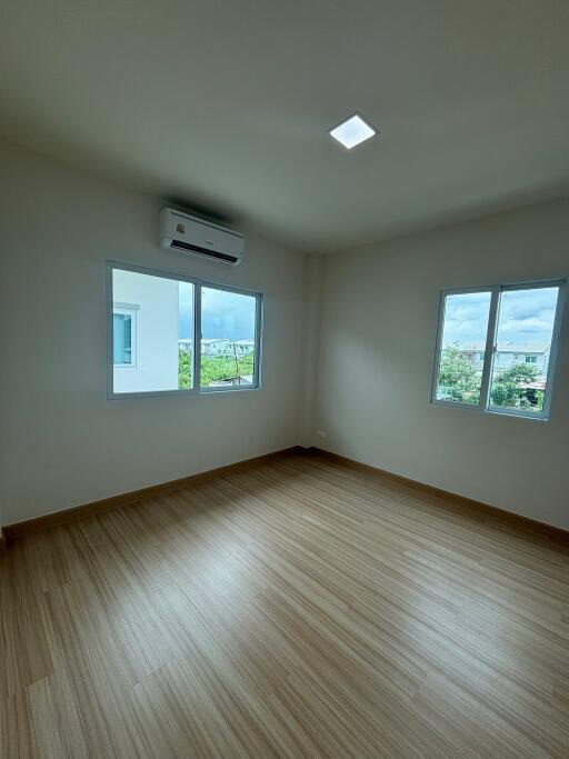 Spacious bedroom with wooden flooring and large windows