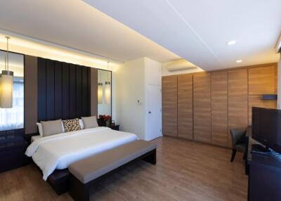 Spacious modern bedroom with wooden flooring and ample natural light