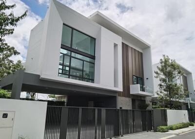 Modern two-story house with large windows and a gated entrance