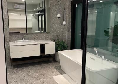 Modern bathroom with a large bathtub, glass shower, and dual sink vanity.