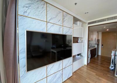 Modern living room with wall-mounted TV and kitchen area