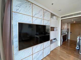 Modern living room with wall-mounted TV and kitchen area