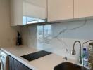 Modern kitchen with white cabinets and marble backsplash