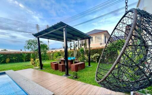 Backyard with pergola, seating area, and hanging chair next to a pool