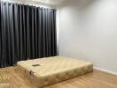 Spacious bedroom with floor mattress and dark curtains