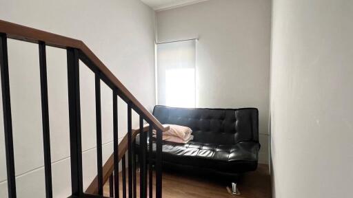 Living area with black sofa and stairs