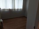 Empty bedroom with hardwood floor and curtained window