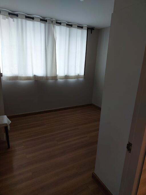 Empty bedroom with hardwood floor and curtained window