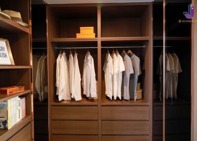 Organized wooden closet with hanging clothes, drawers, and placed items