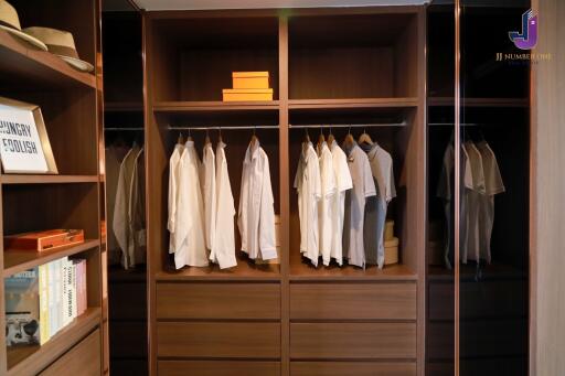 Organized wooden closet with hanging clothes, drawers, and placed items