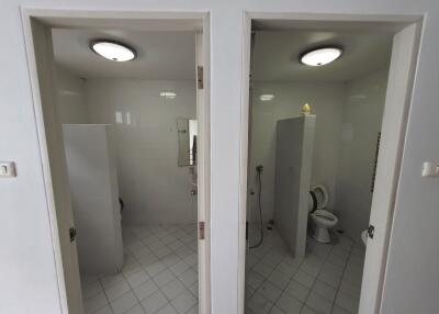 Dual bathroom stalls with white tiled walls and floors