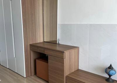 Bedroom with wooden dresser, built-in wardrobe, and decorative lamp