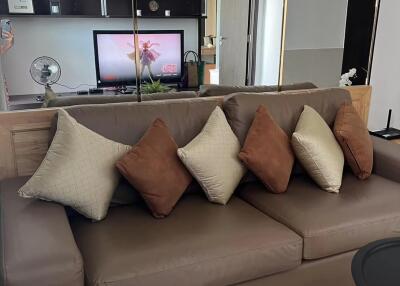 Cozy living room with a brown sofa and decorative pillows, TV, and modern decor