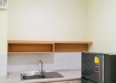 Modern kitchen with a sink, upper shelves, and a refrigerator