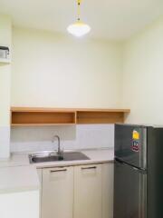 Modern kitchen with a sink, upper shelves, and a refrigerator