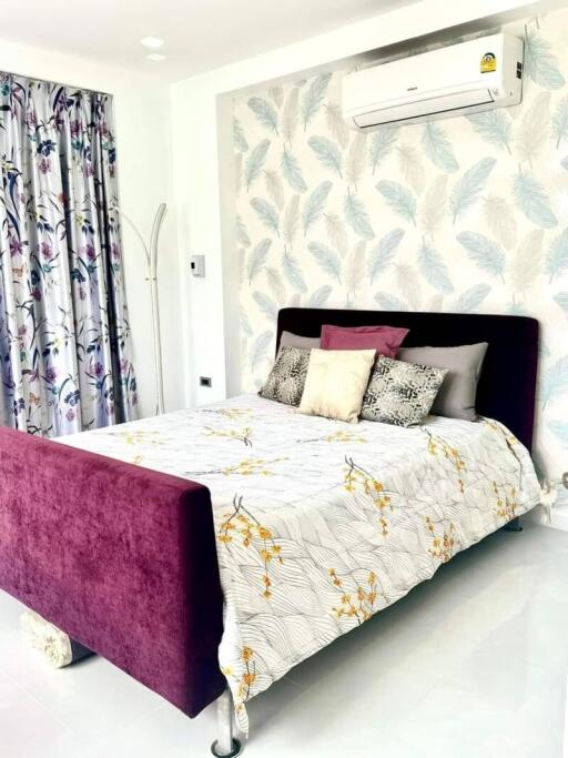 Modern bedroom with a stylish bed, patterned curtains, and wall-mounted air conditioner