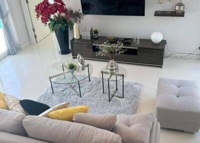 Modern living room with a large grey sofa, wall-mounted TV, and decorative elements