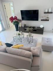 Modern living room with a large grey sofa, wall-mounted TV, and decorative elements