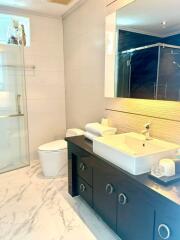 Modern bathroom with a large mirror, shower stall, and vanity counter