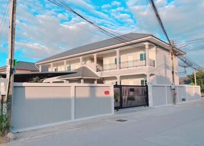 Two-story residential building with tall boundary wall and gate