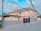 Two-story residential building with tall boundary wall and gate