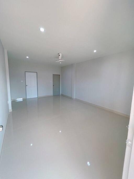 Spacious empty living room with ceiling lights and fan.