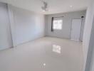 spacious empty living room with white walls and tiled floor