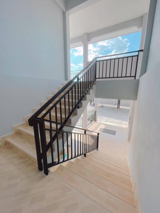 Staircase with black railings and tiled flooring