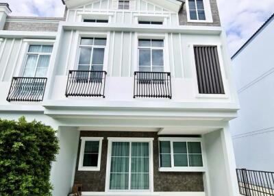 Front view of a two-story modern townhouse with balconies and a carport