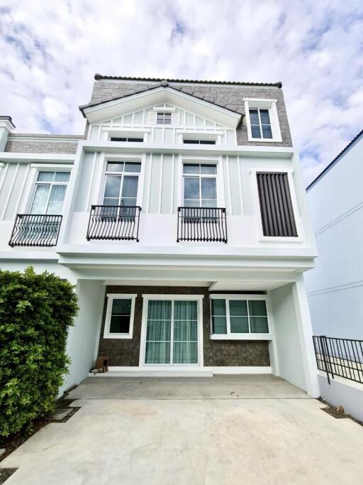 Front view of a two-story modern townhouse with balconies and a carport