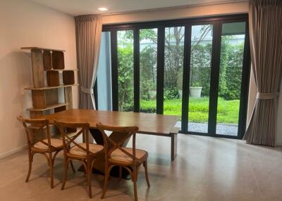 Dining room with wooden table, chairs, and large windows overlooking a garden