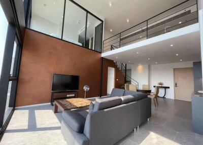 Spacious living room in a modern loft, with large windows and high ceilings