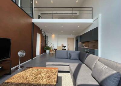 Modern loft living room with large sofa and kitchen area.