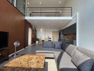 Modern loft living room with large sofa and kitchen area.