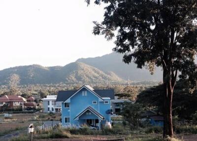 Blue house in a scenic rural area with a mountain backdrop