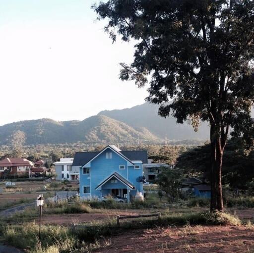 Blue house in a scenic rural area with a mountain backdrop