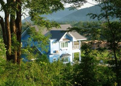 Blue house surrounded by greenery and mountains