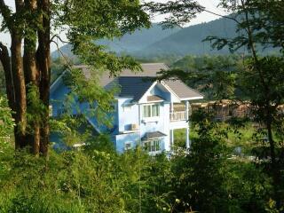 Blue house surrounded by greenery and mountains