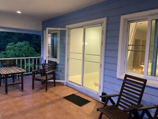 Covered balcony area with seating and large windows