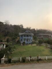 Large blue house with a front yard and surrounding greenery