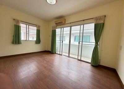 Spacious living room with wooden flooring, large windows, and sliding glass doors leading to a balcony.